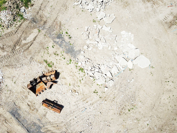 cubo de excavadora vacío pesado en el suelo en un sitio de construcción tomado de una vista de pájaro - Foto, Imagen