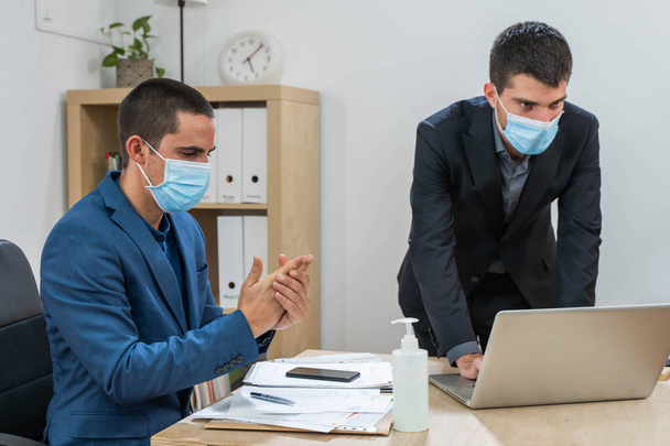 Business worker with face mask back at work in office after lockdown using sanitizer gel. Safety workplace. Office background. New normality.  - Foto, imagen