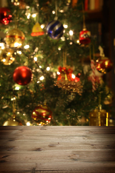 Vánoční pozadí: prázdný dřevěný stůl na popředí a rozostřený vánoční trre na pozadí - Fotografie, Obrázek