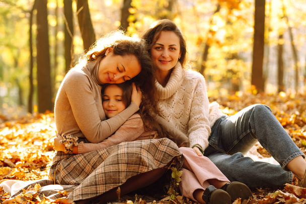 The homosexual family playing with her daughter in the autumn forest. The adventure is more fun when they are together. Autumn women. - Foto, Bild