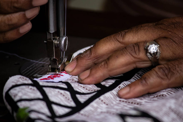 ミシンをかけながら、テーラーメイドの手で布を持ち上げる選択的フォーカス - 写真・画像