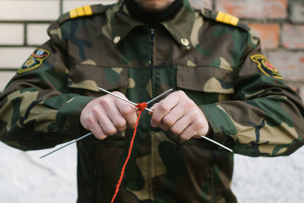 een soldaat in uniform gebreid met naalden en rode draad - Foto, afbeelding
