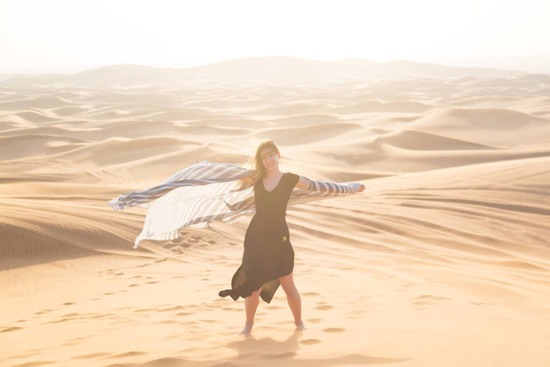 Girl dancing with a white cloth in the desert. Young woman happily smiling dancing with white wide shawl in her hands. - Foto, immagini