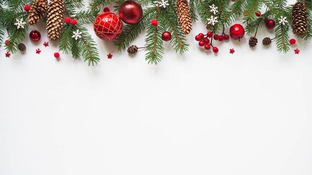 Kerst of nieuwjaar achtergrond, eenvoudige samenstelling van kerst decoratie rode ballen, kegels, sneeuwvlokken en sparren takken op witte achtergrond, platte lay, lege ruimte voor begroeting tekst, kopieer spaes. - Foto, afbeelding