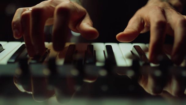Музикант робить музику в темному залі Чоловік натискає клавіші на піаніно в приміщенні
. - Фото, зображення