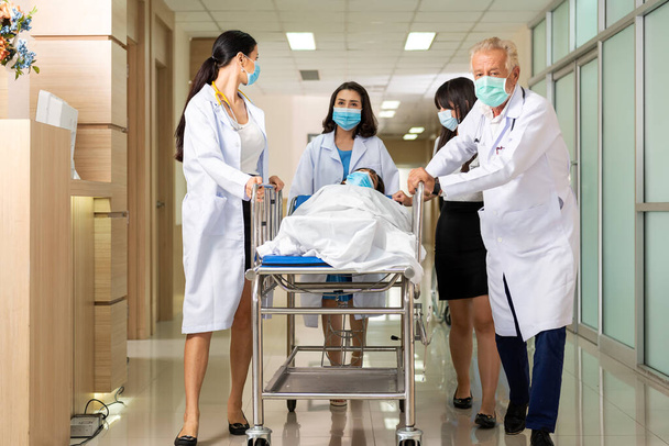 Team medical doctor pushing stretcher gurney bed corridor with female patient in hospital. Health care Concep - 写真・画像
