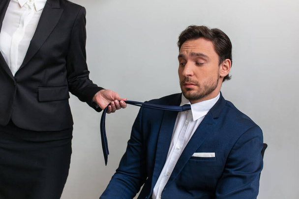 Woman in a business suit pulls a colleague sitting in the office by the tie. Female boss seduces employee. High quality photo - Fotografie, Obrázek