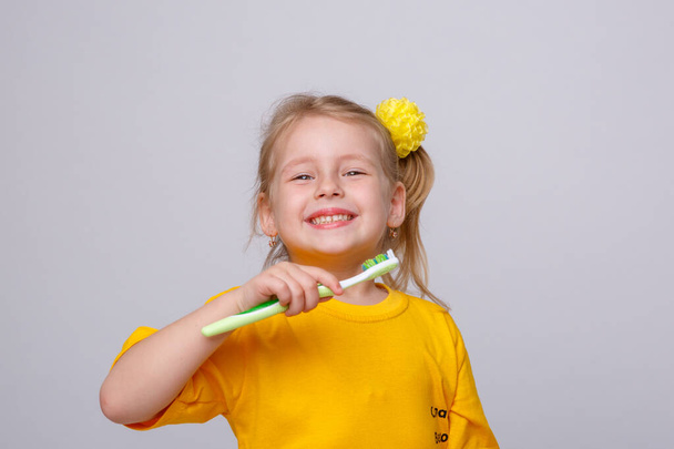 Κοριτσάκι με οδοντόβουρτσα. Κοριτσάκι με οδοντόβουρτσα και μήλο. Η έννοια της καθημερινής υγιεινής. Απομονωμένα σε λευκό φόντο - Φωτογραφία, εικόνα