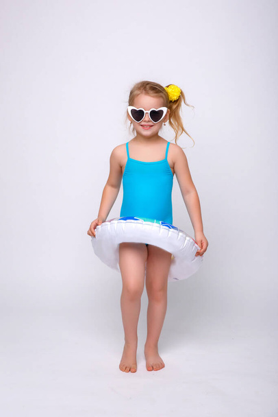 Roztomilé usměvavé děvčátko v plavkách s gumovým kroužkem izolovaným na bílém. Módní holčička v plavkách. - Fotografie, Obrázek