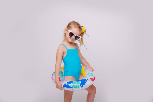 Cute smiling little girl in swimsuit with rubber ring isolated on a white. Fashionable little girl in swimsuit. - Zdjęcie, obraz