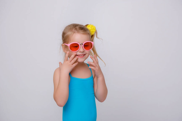 Jolie petite fille souriante en maillot de bain avec anneau en caoutchouc isolé sur un blanc. Petite fille à la mode en maillot de bain. - Photo, image