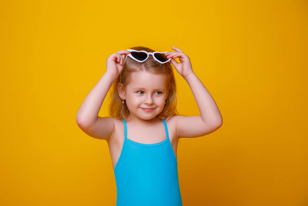 girl in a swimsuit and sunglasses on a yellow background - Photo, Image