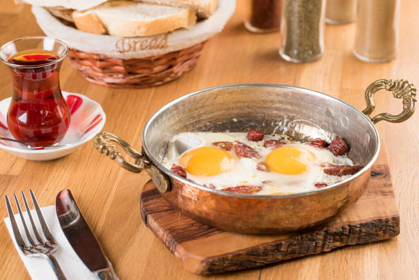 Традиционный турецкий завтрак - жареное яйцо с турецкой колбасой. Хлеб и чай - Фото, изображение