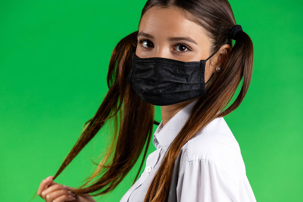 Big eyes girl wearing protective black face mask. Young beautiful brunette model. Copy, empty space - Foto, afbeelding
