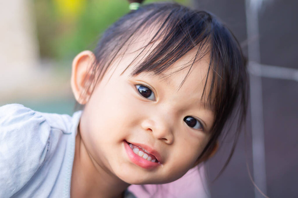 Portraitbild eines 2 bis 3 Jahre alten Babys. Glückliches asiatisches Kindermädchen lächelnd und mit Stoffmaske. Sie spielt auf dem Spielplatz. Soziale Distanz. Lern- und Aktiv-Konzept für Kinder. - Foto, Bild