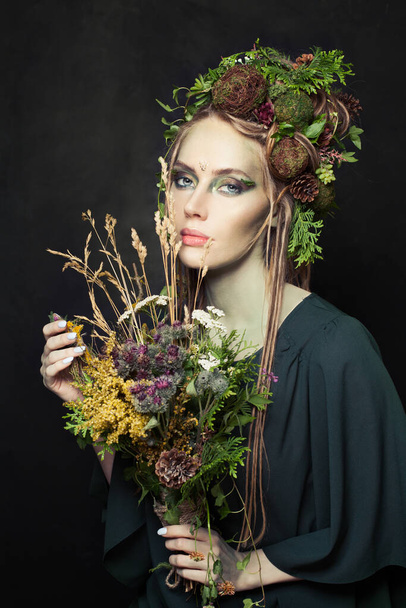 Halloween character woman with creative makeup, flowers, green leaves and tree bark on black - Foto, afbeelding