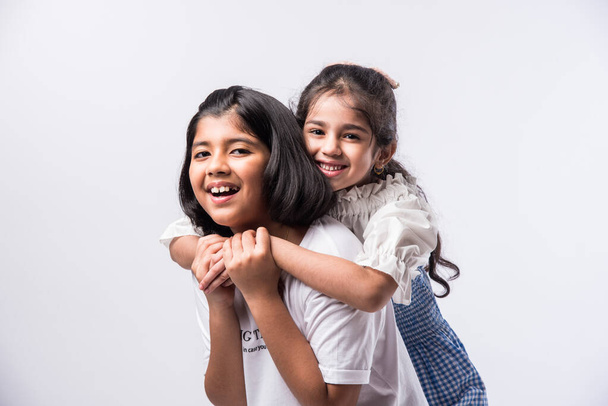 Cute little Indian asian siblings standing and embracing each other in white clothes while standing againstwhite background. - Φωτογραφία, εικόνα