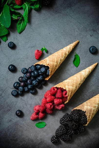 Fresh berries in waffle cones on dark stone background, top view. Concept healthy food and desert. - Foto, immagini