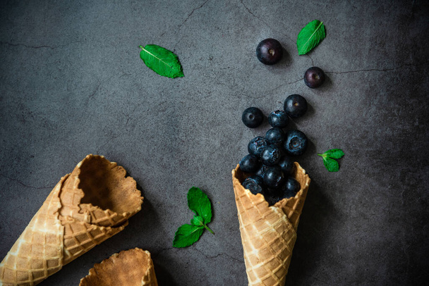 Blueberries in waffle cones on dark stone background, top view. Concept healthy food and desert. - Zdjęcie, obraz