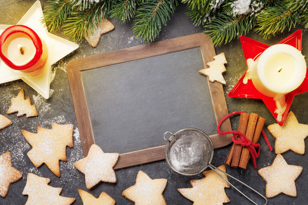 Χριστουγεννιάτικη ευχετήρια κάρτα με έλατο, μπισκότα μελόψωμου και κεριά σε πέτρινο φόντο. Top view επίπεδη θέσει με chalkboard για σας Χριστούγεννα χαιρετισμούς - Φωτογραφία, εικόνα