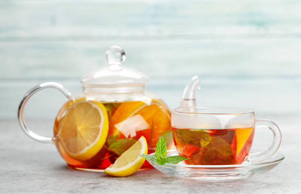 Tradycyjna herbata owocowa w czajniczku i szklana z cytryną, jagodami i miętą - Zdjęcie, obraz