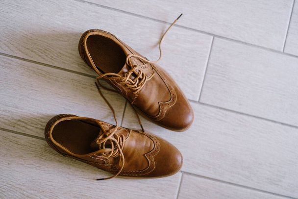 Zapatos para hombre marrón con cordones desatados en un laminado blanco. - Foto, imagen
