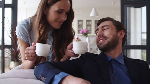 Hymyilevä pari juomassa teetä kotona yhdessä. Iloinen pari kahvitauolla - Valokuva, kuva