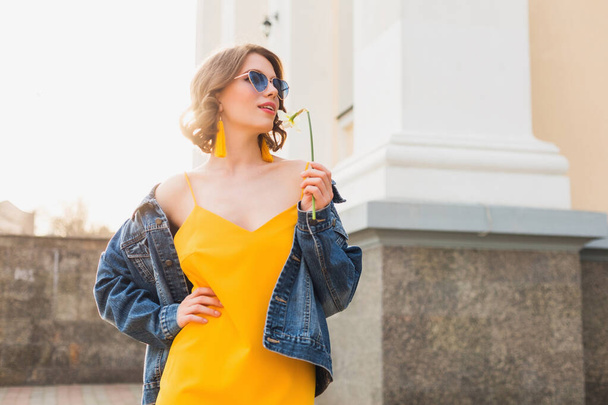 beautiful sexy stylish woman in yellow stylish dress wearing denim jacket, trendy outfit, spring summer fashion trend, sunny, blue sunglasses, street fashion, hipster style, fashionable accessories - Foto, immagini