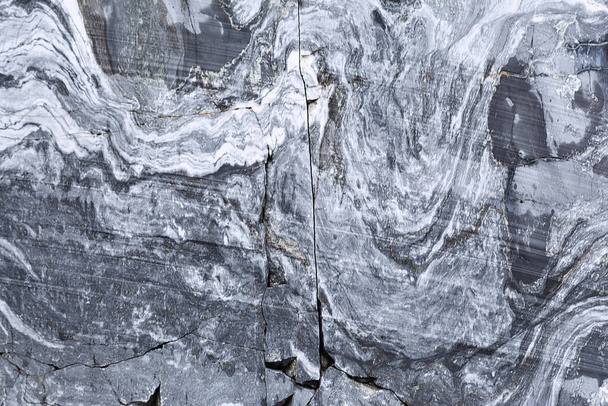Η υφή ενός μαρμάρινου βράχου με ρωγμές και μοτίβο σε μορφή ραβδιών. Έννοια φόντο, υφή, φύση - Φωτογραφία, εικόνα