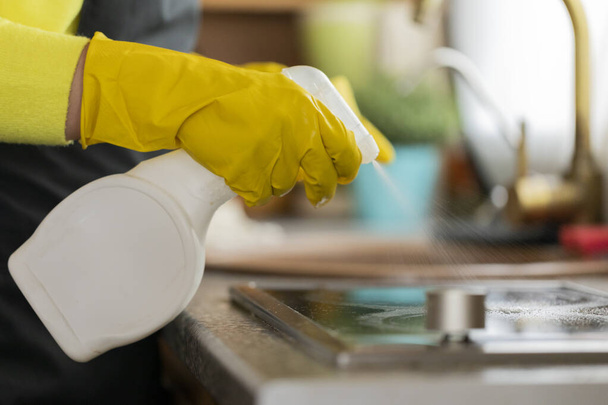 Close up view of person in rubber gloves cleaning kitchen worktop using spray - 写真・画像