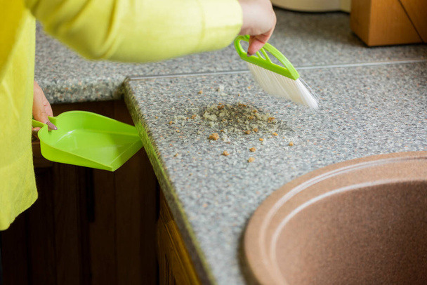 Close up pessoa varre migalhas fora da mesa com escova e dustpan conjunto para cozinha - Foto, Imagem