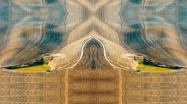 pond for irrigation in a cultivated but arid field. Two tractors near the water are waiting to get back to work.Under the grazing light of sunset, thousands of plows in the soil draw geometric shapes in the barren ground. - Photo, Image