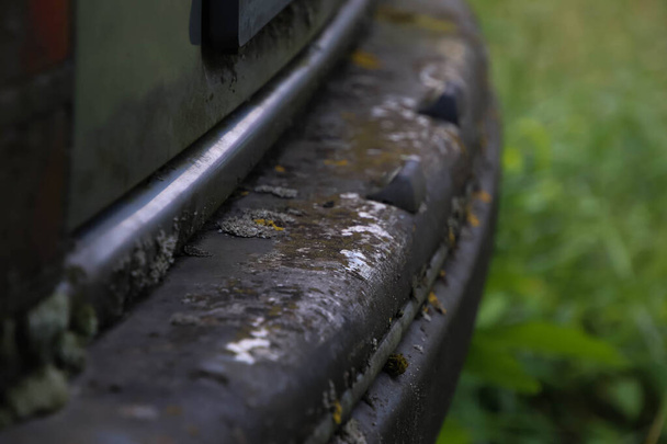 Vista laterale di un'auto d'epoca abbandonata bar posteriore pieno di polvere arrugginita di muschio.Primo piano del retro dell'auto e del muschio. - Foto, immagini