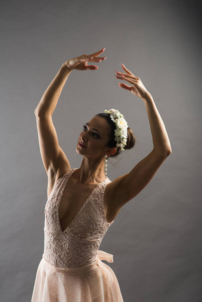 giovane bella ballerina di balletto in costume da bagno beige in posa su punti su sfondo grigio chiaro studio - Foto, immagini