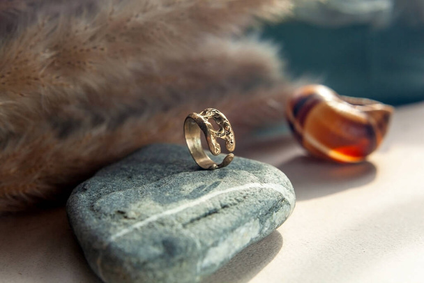 anel de bronze fundido vintage na moda. jóias mulheres anel abstrato desenho closeup em uma pedra natural cinza com shaddows - Foto, Imagem