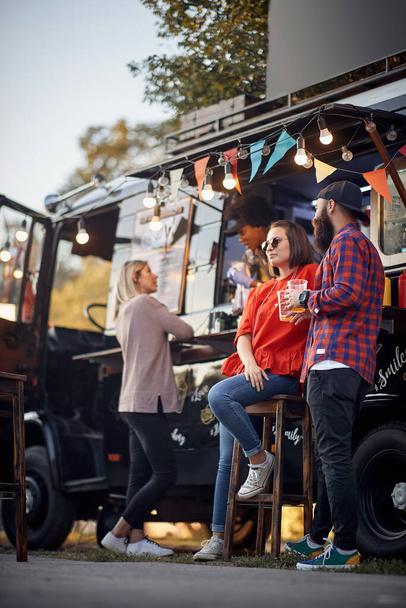 Friends chilling out with beer in front of food truck - Fotoğraf, Görsel
