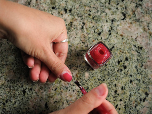 Hand of a young woman painting her red nails - Photo, Image