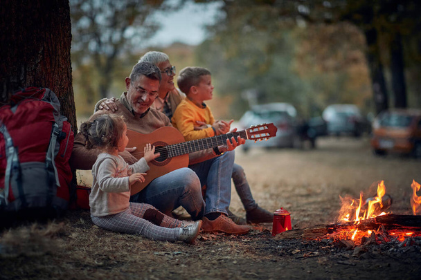 Grandparents singing with grandchildren on camping; Quality family time concept - Photo, Image