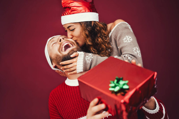 Happy couple celebrating Christmas time sharing gift box - Young lovers having fun during xmas holidays - Youth lifestyle culture and people traditional event concept - Photo, Image