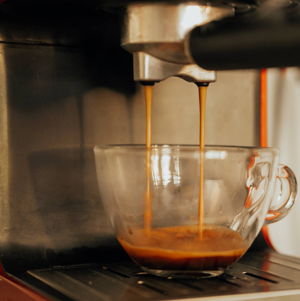 closeup view of coffee made in professional espresso machine pouring into a cup - 写真・画像