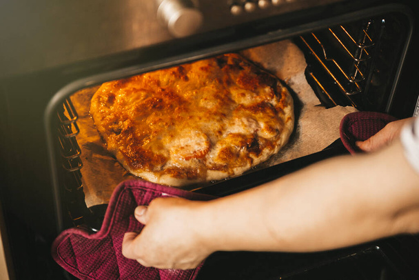 vista de cerca de las manos de la mujer tomar pizza caliente del horno - Foto, Imagen
