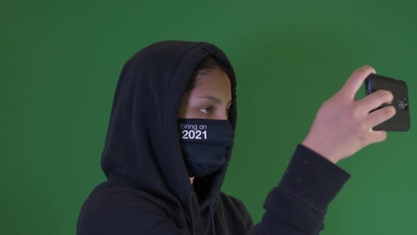 Kadın kapüşonlu ve 2021 'de elinde akıllı telefon maskesi olan bir genç kız. Yeşil Ekran, Kilitli - Video, Çekim