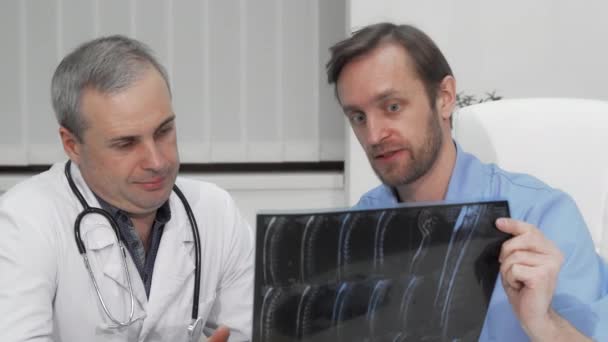 Due medici maschi maturi discutono la risonanza magnetica del paziente - Filmati, video