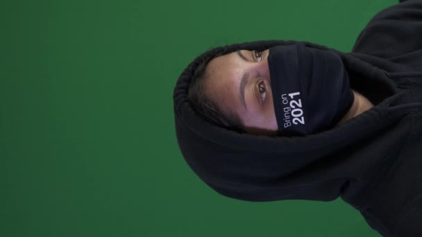Donna adolescente che indossa una felpa con cappuccio e la porta sulla maschera per il viso 2021. Schermo verde, Video verticale, Bloccato - Filmati, video