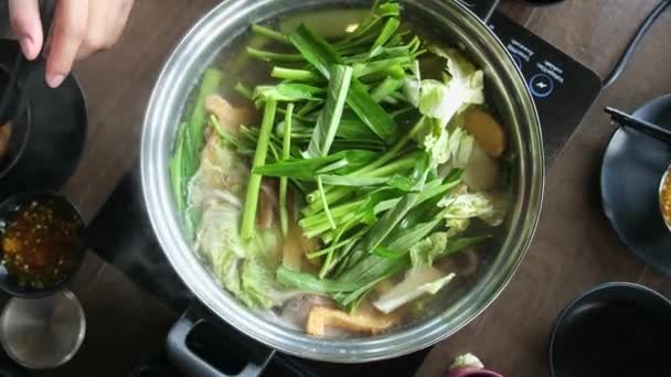 top view mensen eten Aziatische Shabu Shabu of Sukiyaki met vers voedsel koken in hete kook soep met groenten vlees in hot pot in restaurant, populair eten in Thailand - Video