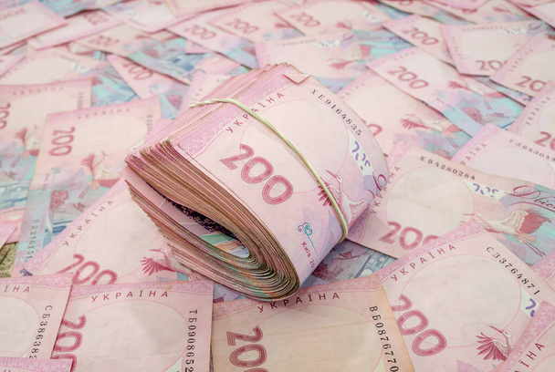 egy rakás hrivnya, anyagi háttérrel. 200 hrivniai ukrán bankjegy, gumiszalaggal kötve. - Fotó, kép
