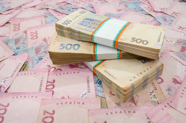 три пачки украинских гривен на денежном фоне. Украинские купюры номиналом 500 гривен. - Фото, изображение