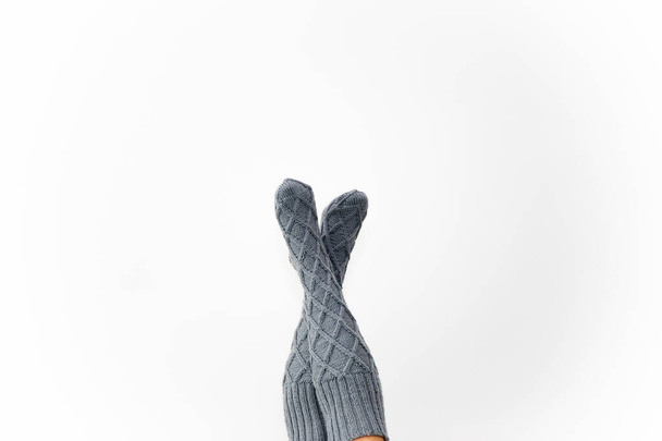 Chaussettes de genou tricotées grises sur les jambes sur un fond blanc. - Photo, image