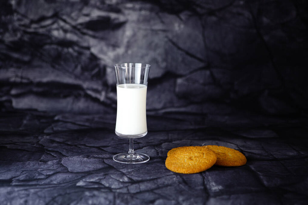 Glass of milk with round cookies on a black background - Photo, image