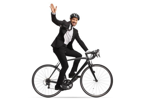 Profile shot of a businessman riding a bicycle to work and waving at camera isolated on white background - Foto, Bild